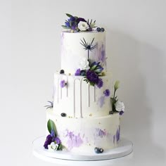 a three tiered cake with purple and white flowers