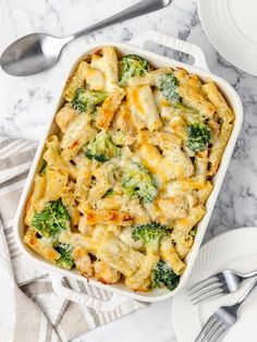 a casserole dish with chicken and broccoli in it on a marble table