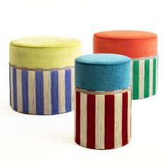 three different colored stools sitting next to each other on a white surface with stripes