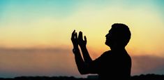 the silhouette of a person holding their hands up in front of a sky with clouds