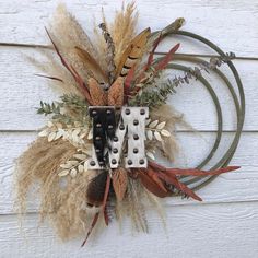 a wreath made out of metal and feathers on a white wooden wall with the word fall written in it