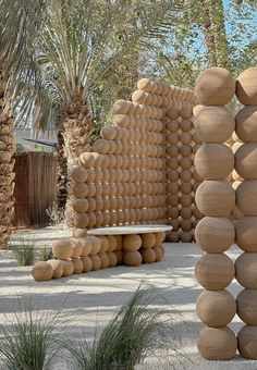 an outdoor sculpture made out of rocks in the middle of a desert area with palm trees behind it