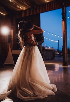 the bride and groom share their first dance together in an old barn at night time