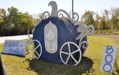 there is a blue and white horse drawn carriage on the grass in front of a street sign