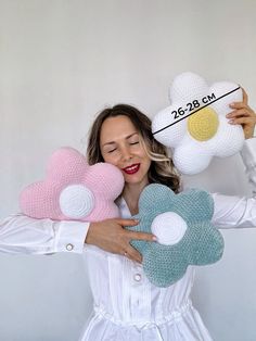 a woman is holding three flower pillows in her hands