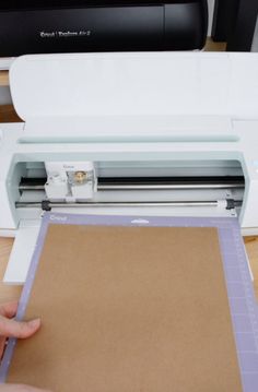 a person is cutting paper with a cricut machine on a table next to a printer