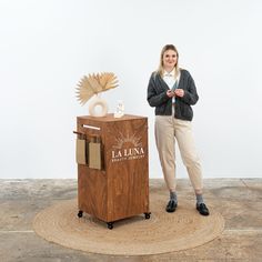 a woman standing next to a wooden box with an object on it's side