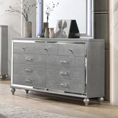 a silver dresser sitting in front of a mirror