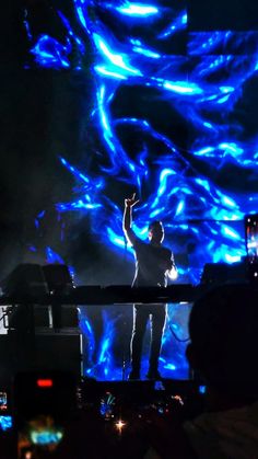 a man standing on top of a stage in front of a blue light filled background