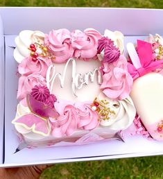 a pink and white cake in a box with the word mom written on it's side