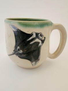 a ceramic coffee cup with a black and white stingfish on it's side