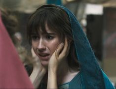 a woman talking on her cell phone while wearing a blue shawl over her head