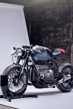 a motorcycle is parked in front of a white wall and some black metal bars on the sides