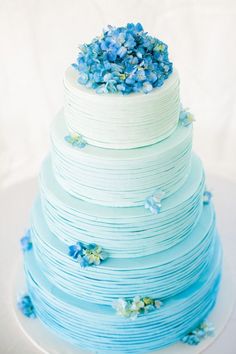 a blue and white wedding cake with flowers on top