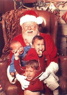 an old man sitting in a chair with three children and one is holding his mouth open