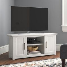 a flat screen tv sitting on top of a white entertainment center in a living room