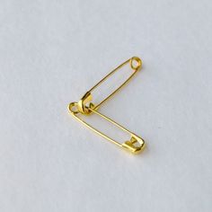 a pair of gold - plated metal clips on a white surface, with one clip in the shape of a rectangle