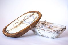 two wooden boxes with rope tied to them on a white surface, one is empty and the other is closed