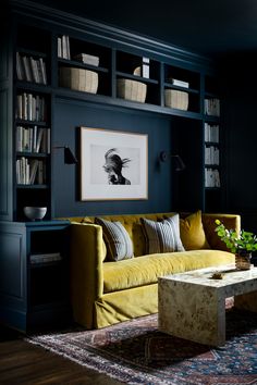 a living room with bookshelves and a couch in the corner, next to a coffee table