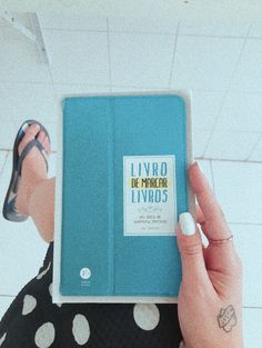 a person holding up a blue book in their left hand, with the title livro de princess livros written on it