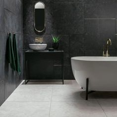 a white bath tub sitting under a bathroom mirror