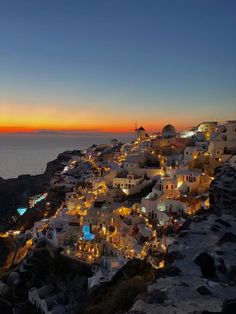 the sun is setting over some white buildings on top of a hill near the ocean