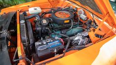 the engine compartment of an orange car with its hood open