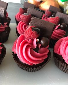 chocolate cupcakes with raspberry frosting and candy on the top are ready to be eaten