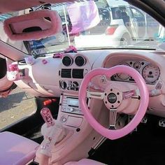 the interior of a car with pink steering wheel and dash board, decorated with bows