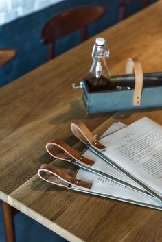 three pairs of scissors sitting on top of a wooden table next to a bottle of wine