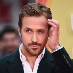 a close up of a person wearing a suit and holding his hand to his head