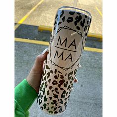 a person holding up a leopard print tumbler cup with the word ma on it