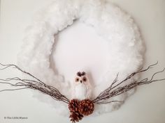 an owl is sitting in the middle of some branches with pine cones on it's head