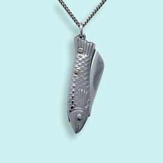 A tiny silver fish folding knife with a sharp blade on a silver curb chain. Metal: Stainless steel blade, plated brass chain. Size: 1" L knife Lobster Clasp Available in 16", 18", and 20" chain (18" Fits Most) Chain is made in the USA, Knife is made in China Word to the wise: This is a real knife and the blade is sharp. Don't wear it with the knife open. Keep it out of reach of children. Use caution when opening and closing it (if you've never opened a pocket knife, please take a minute to find Gold Compass Necklace, Knife Necklace, State Necklace, Fish Knife, Fish Necklace, 40th Gifts, Compass Necklace, Silver Fish, Silver Chain Bracelet