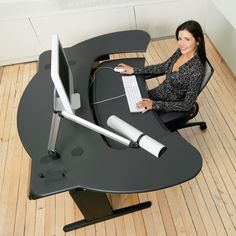 a woman sitting at a computer desk with a monitor and keyboard in front of her