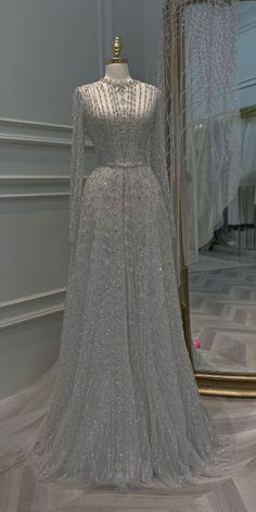 a wedding dress on display in front of a mirror with long sleeves and beading