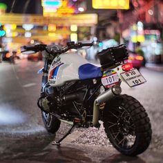 the motorcycle is parked on the side of the road in front of some buildings at night