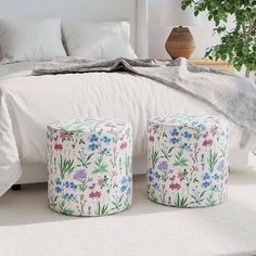 a bedroom with white bedding and flowers on the pillows, two stools in front of the bed