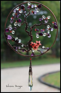 a wind chime with beads hanging from it's sides and a tree on top