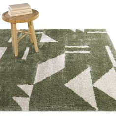 a green rug with white arrows on it next to a wooden table and stools