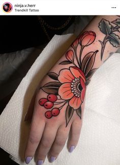 a woman's hand with flowers and berries tattooed on the left side of her arm