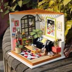 a doll house with furniture and pictures on the wall next to potted plants in front of it