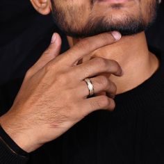 a close up of a person wearing a ring and holding his hand to his chin