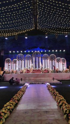 an elaborate decorated stage with flowers and lights on the ceiling is lit up at night