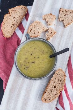 a bowl of soup and some slices of bread on a towel with a red and white striped napkin