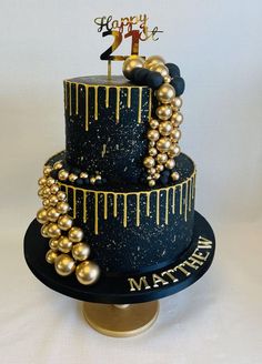 a three tiered cake with gold and black decorations on it's side that says happy birthday