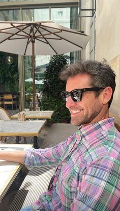 a man wearing sunglasses sitting at an outdoor table