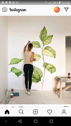 a woman is painting a plant on the wall