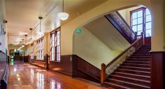 an empty hallway with wooden floors and stairs leading up to the second floor in a building