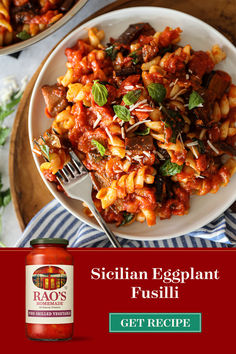 two plates of pasta with sauce and basil on the side, next to a jar of italian eggplant fusili